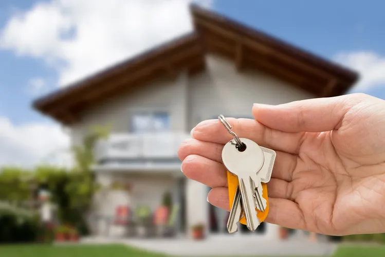 Keys to a managed residential property held in front of a home
